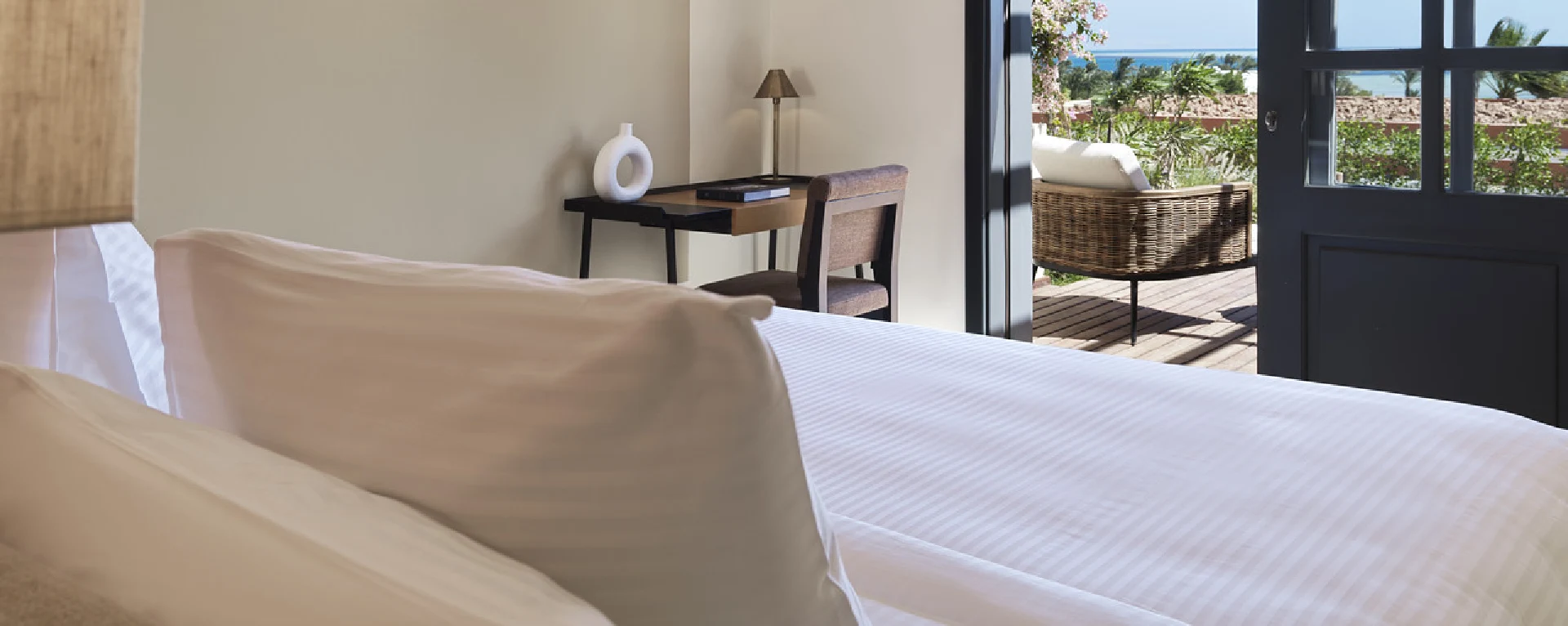 Room at Chedi El Gouna with open balcony offering scenic views of the sea, furnished with comfortable seating and elegant decor.