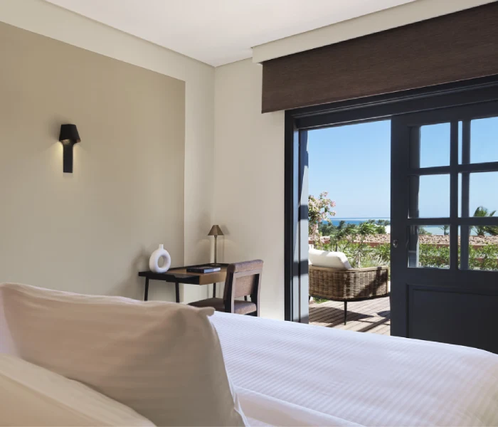 Room at Chedi El Gouna with open balcony offering scenic views of the sea, furnished with comfortable seating and elegant decor.