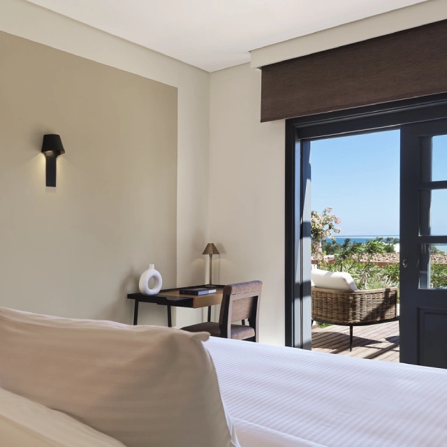 Room at Chedi El Gouna with open balcony offering scenic views of the sea, furnished with comfortable seating and elegant decor.