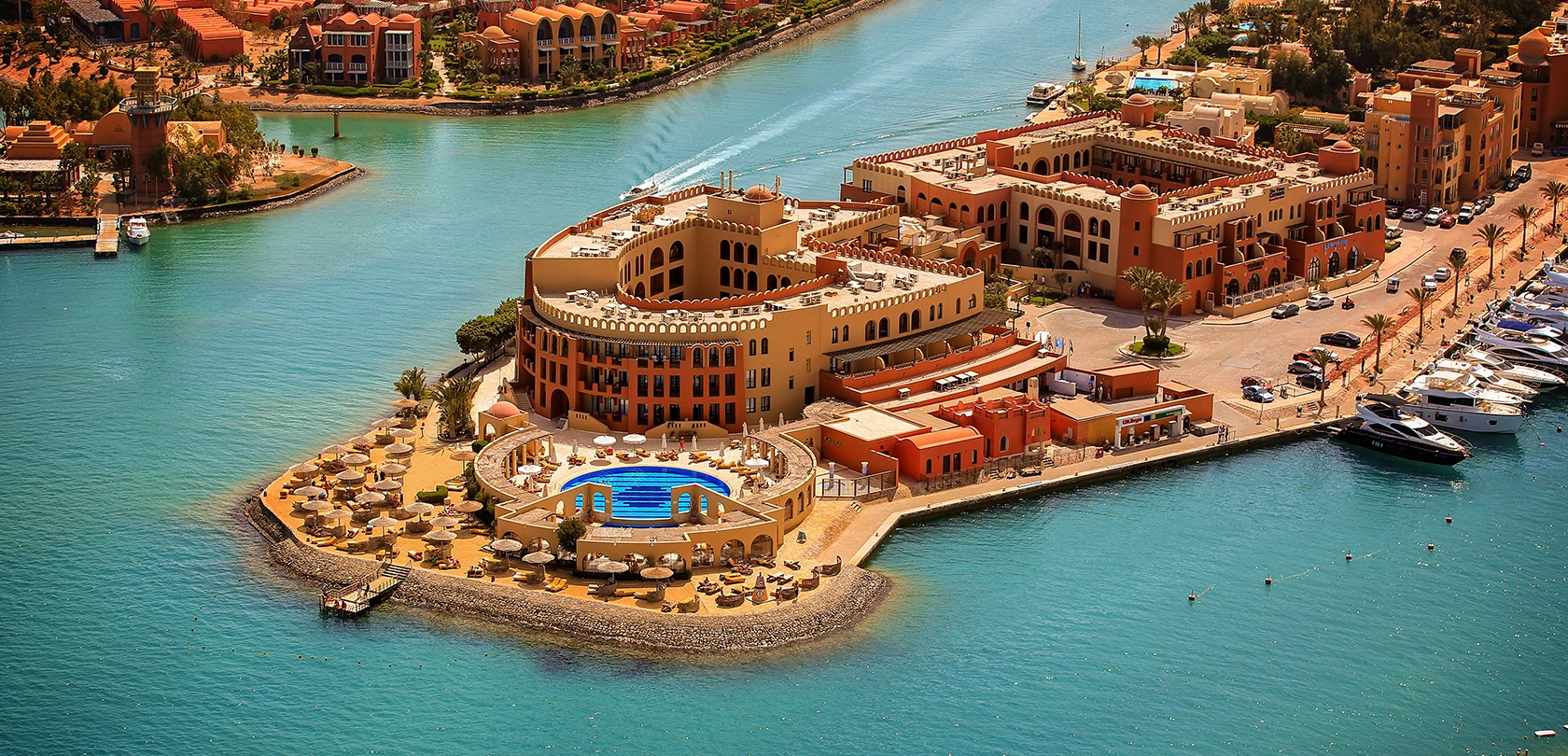 Aerial view of Three Corners Ocean View resort featuring a large pool, sun loungers, and surrounding turquoise waters, highlighting its prime coastal location.