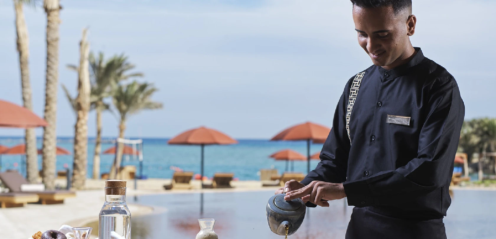 Waiter pouring tea at Chedi El Gouna, with a breathtaking view of the sea in the background.