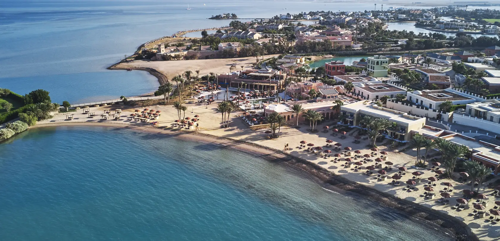 Aerial view of Chedi Hotel with expansive sea view in the background, showcasing its architectural design and coastal setting.
