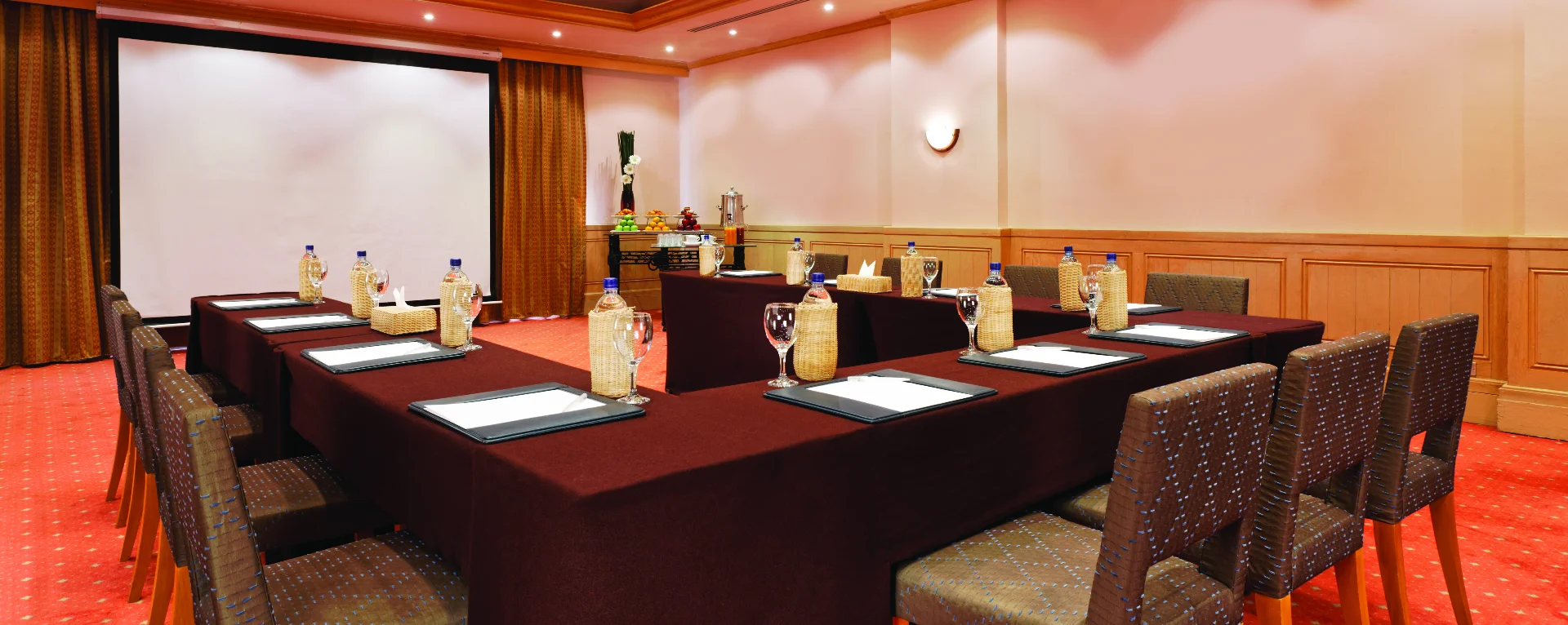 A meeting room at Mövenpick Hotel El Gouna with table, chairs, and a projector screen.