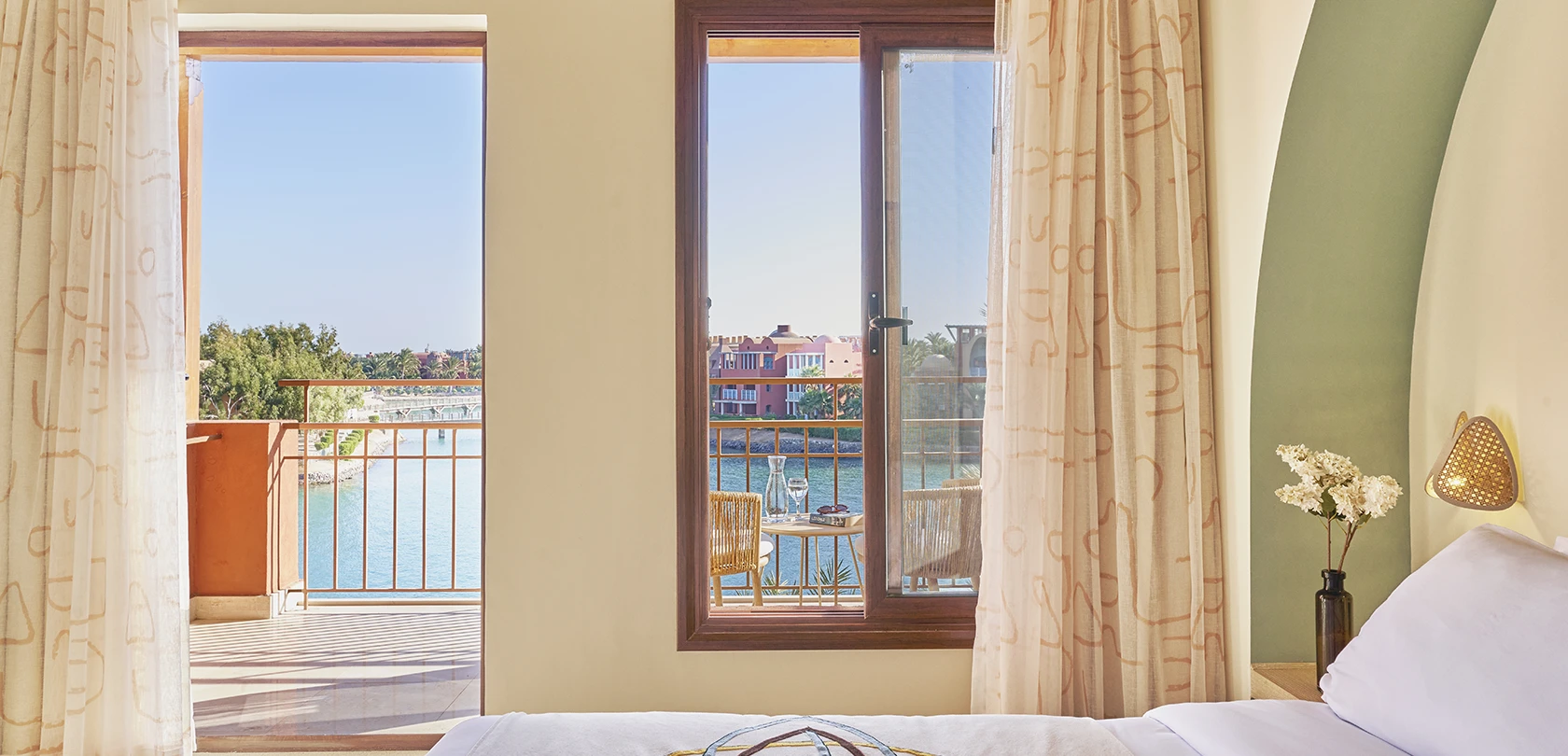 A spacious Superior Room with a king-sized bed at Three Corners Ocean View, El Gouna, Red Sea. The room offers a stunning sea view from a private balcony, featuring modern furnishings, soothing neutral tones, and large windows that flood the space with natural light.