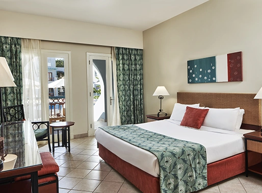King bedroom at Red Sea, Egypt, featuring a luxurious king-sized bed with soft linens, stylish decor, and modern furnishings. The room is well-lit and designed for comfort, providing a relaxing and elegant space for guests to unwind.
