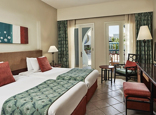 Twin bedroom at Red Sea, Egypt, featuring two single beds with crisp linens, modern decor, and stylish furnishings. The room is bright and inviting, designed for comfort and relaxation, with a warm color palette and ample amenities.