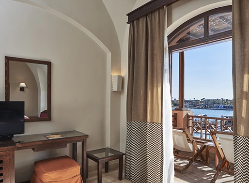 Room at El Gouna Red Sea, Egypt, with a lagoon view, featuring a television mounted on the wall and a large mirror. The room is designed with modern furnishings and offers a scenic view of the lagoon, providing a comfortable and stylish environment for guests.